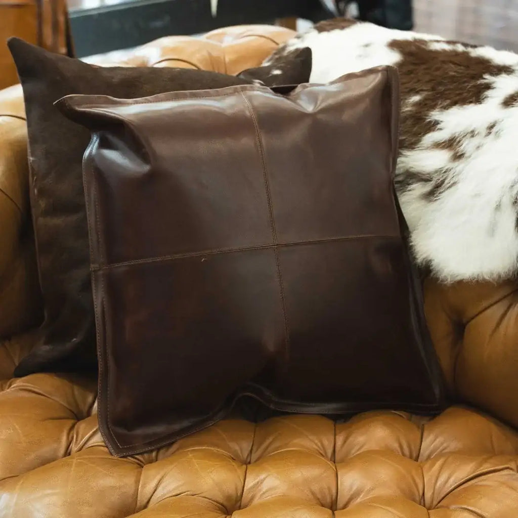 Brown leather pillow on tan tufted leather sofa with cowhide accent