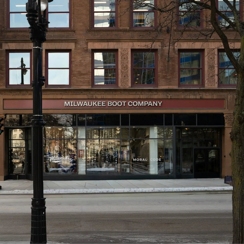Storefront with large windows and sign reading Milwaukee Boot Company on brown brick building