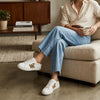 Woman wearing light jeans and leopard print white sneakers sitting on a beige sofa