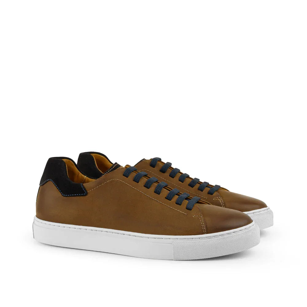 Brown leather sneakers with black heel accent, navy laces, and white rubber soles