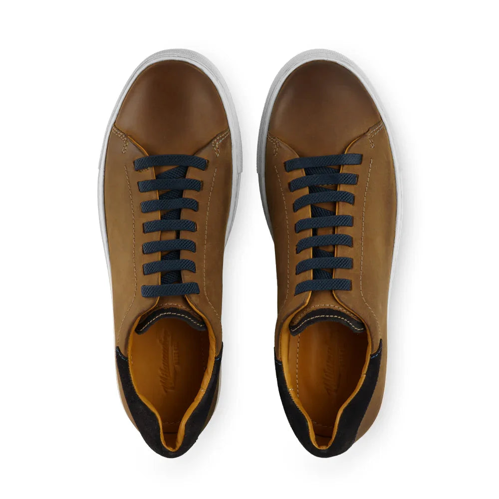 Brown leather low-top sneakers with black laces and white soles, top-down view