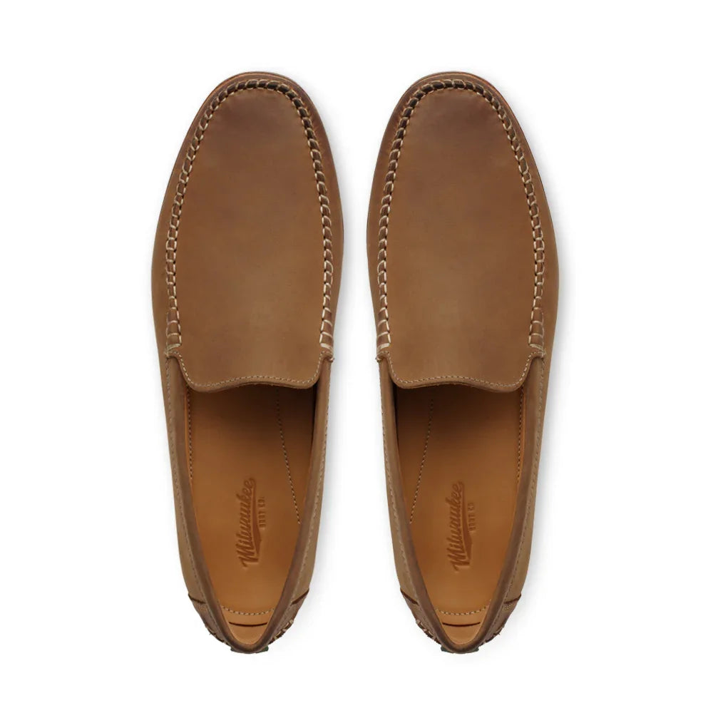 Top view of tan leather loafers with visible stitched detailing on white background