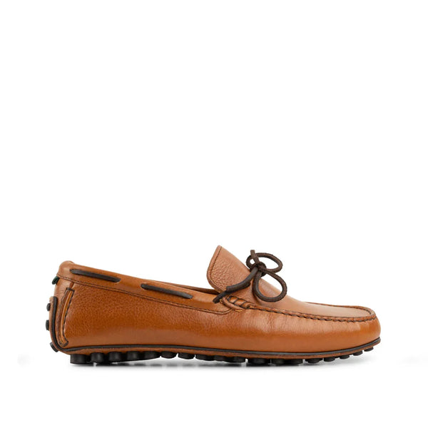 Cognac brown leather loafer with moc toe and black driving sole on white background