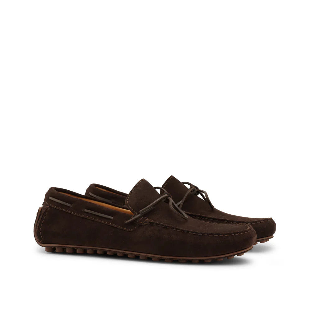 Pair of dark brown suede loafers with moc toe and rubber stud sole, side view on white background