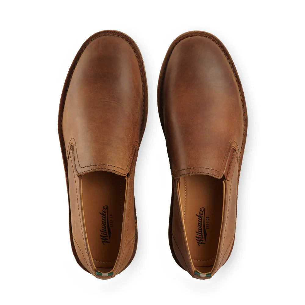 Pair of camel brown leather slip-on boots on a white background, top view.