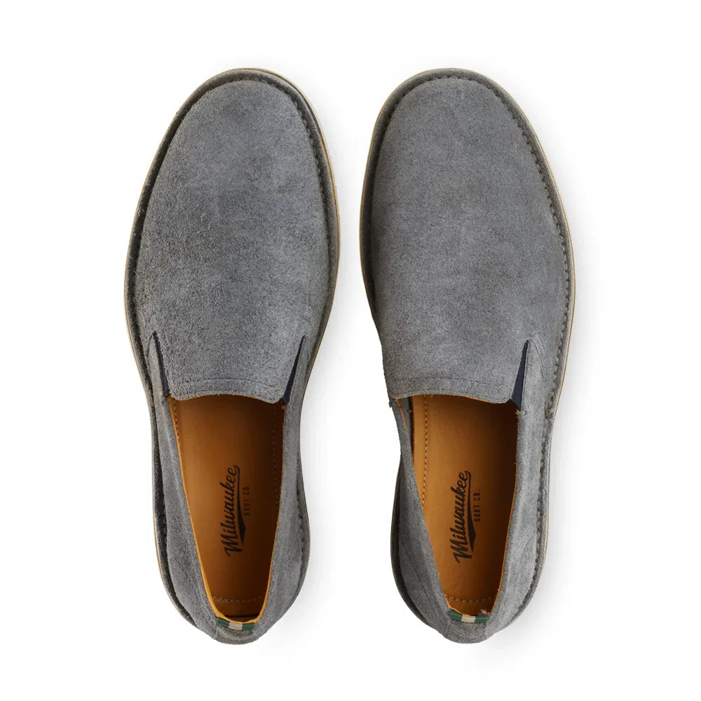 Top view of gray suede slip-on shoes with tan leather insoles on a white background.