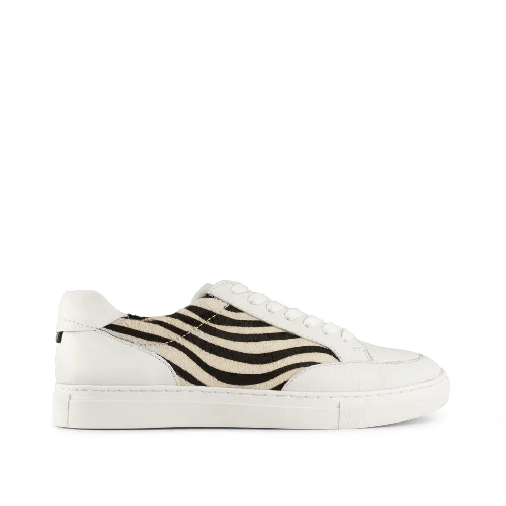 White low-top sneaker with black zebra stripe pattern side panel, lace-up design