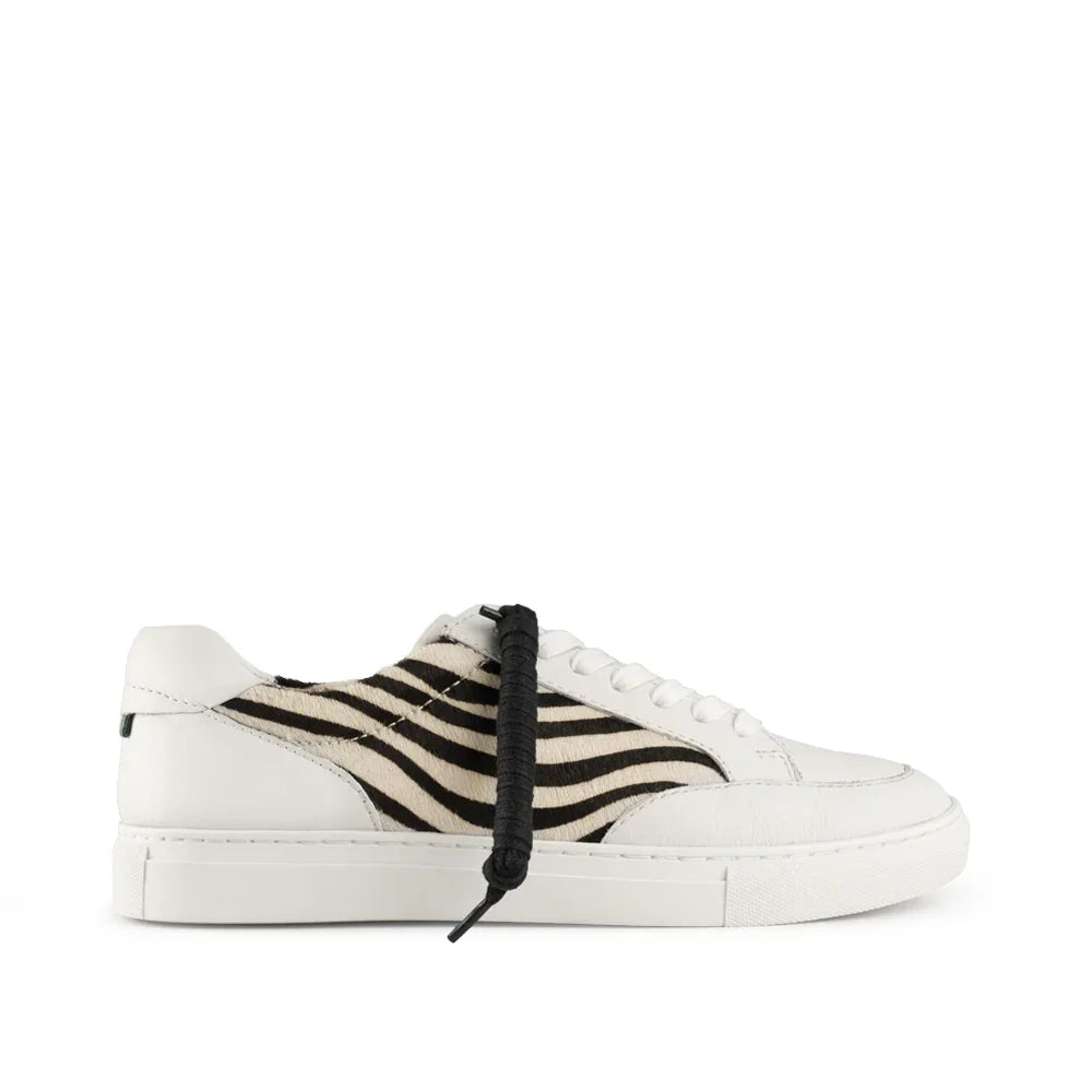 White low-top sneaker with black and white zebra pattern side panel and extra black lace
