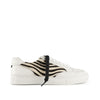 White low-top sneaker with black and white zebra pattern side panel and extra black lace