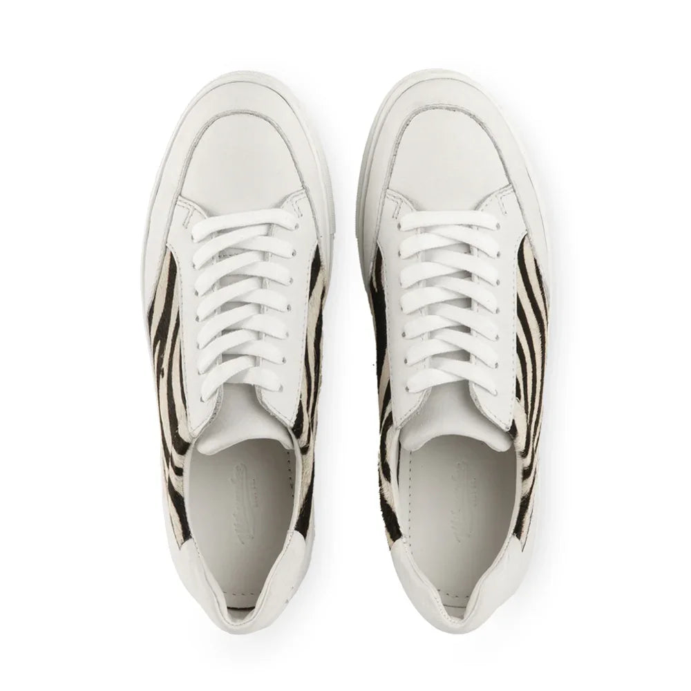 White low-top sneakers with zebra print side panels, top view on white background
